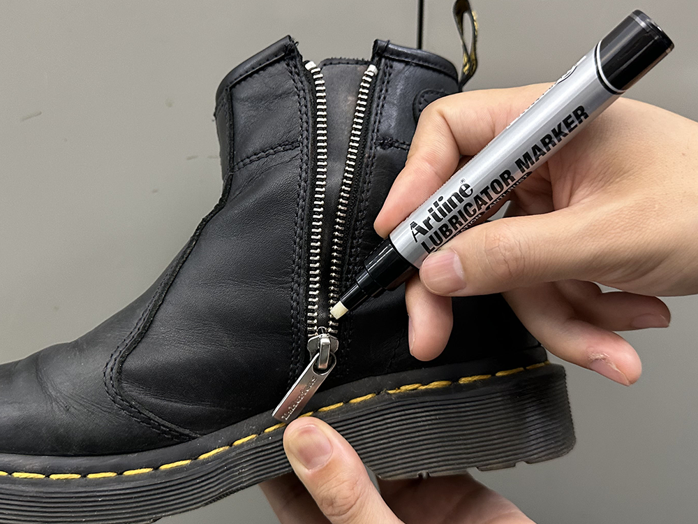 Putting lubricator ink onto zipper of leather boot with Artline LUBRICATOR MARKER